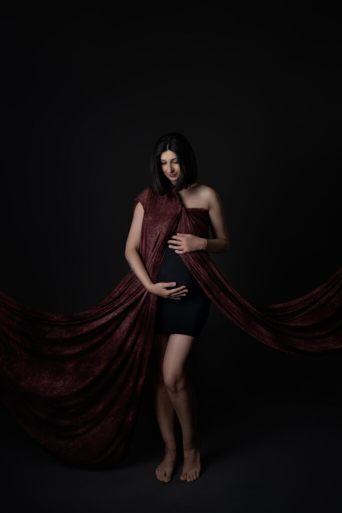 Zwangere vrouw in bordeaux rode outfit tijdens een zwangerschap fotoshoot bij Little Miracle memories