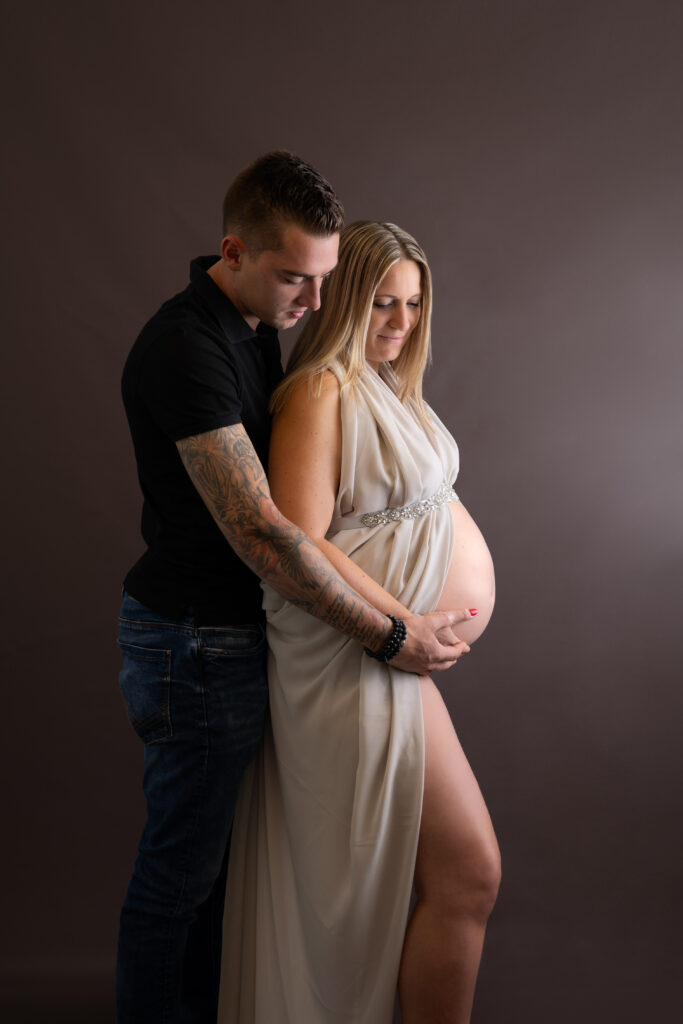 Zwangere vrouw in zand kleurig outfit samen met haar man in zwarte outfit tijdens een zwangerschap fotoshoot bij Little Miracle memories