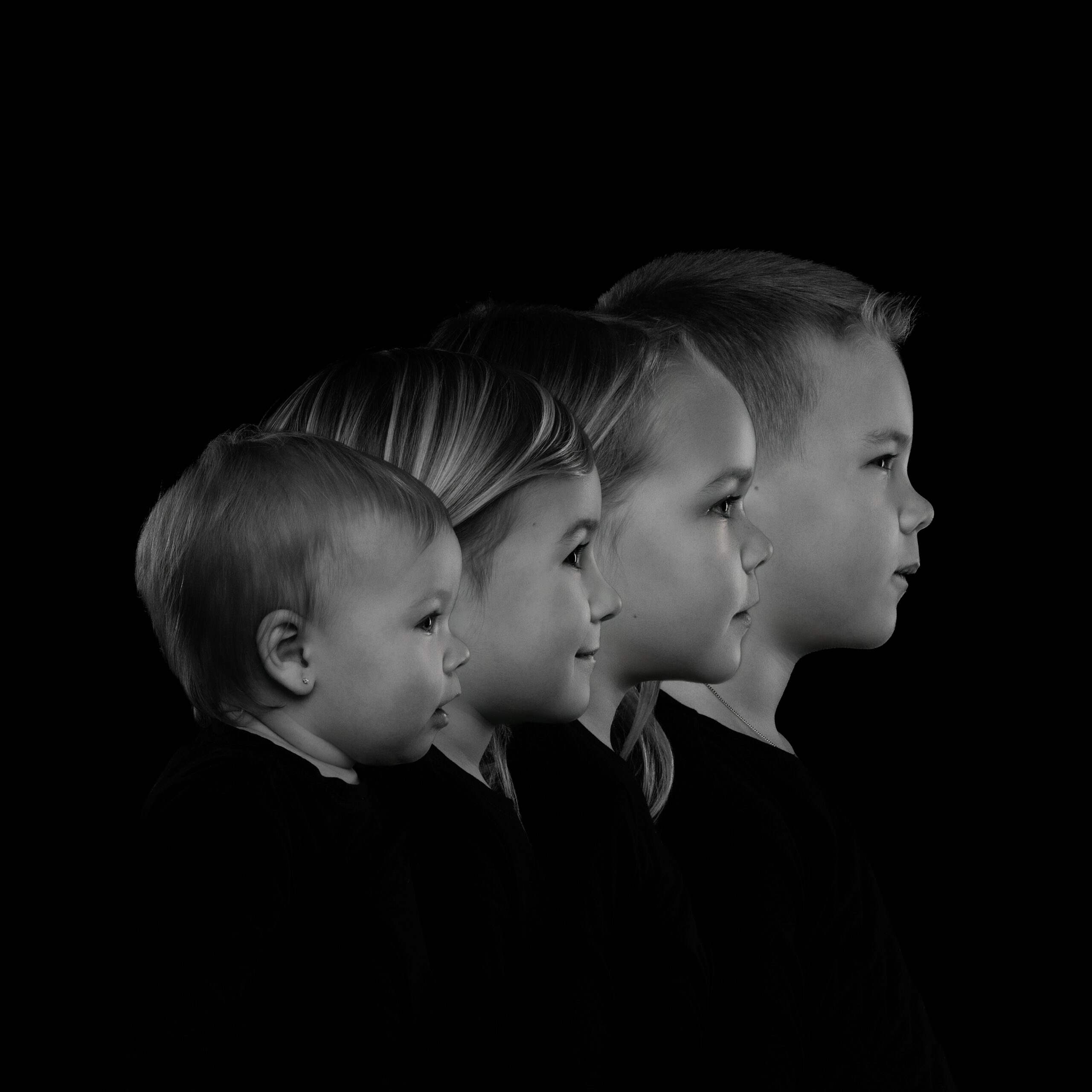 Zwart-wit portret van vier kinderen uit één gezin in profiel, van baby tot oudste kind, vastgelegd als tijdloos familieportret in de fotostudio in Zandhoven
