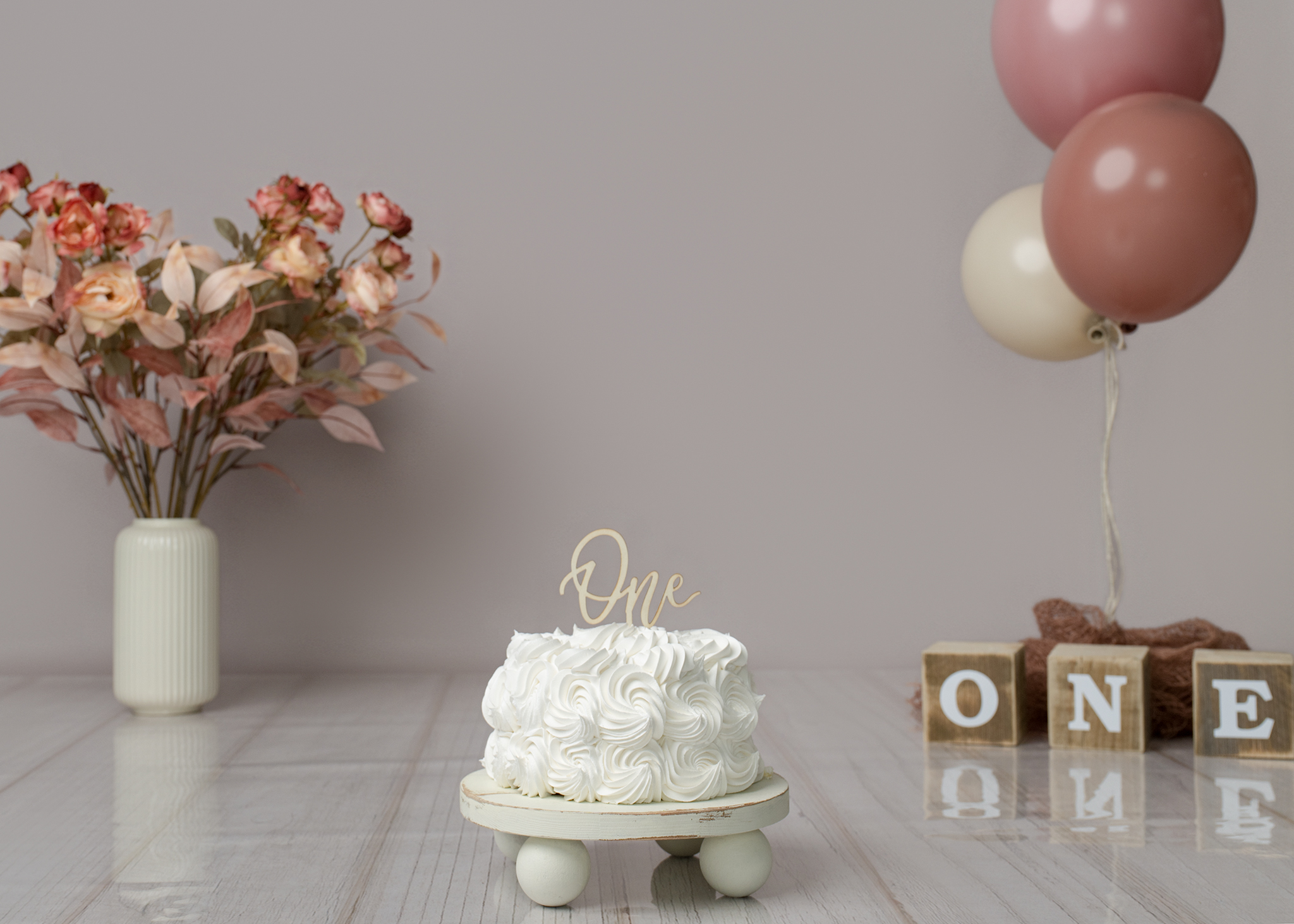 Cakesmash setup met roze thema - witte taart met "one" topper, roze ballonnen en bloemen