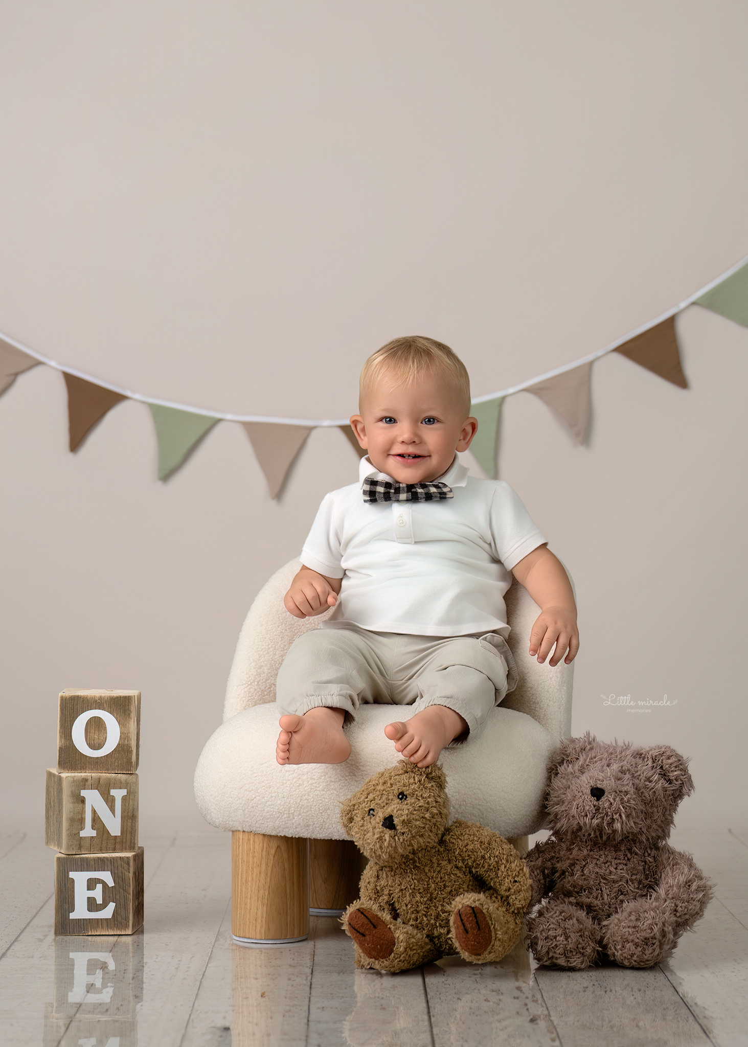 Jongen van één jaar zittend met een teddybeer, gefotografeerd van achteren tijdens een eerste verjaardag fotosessie